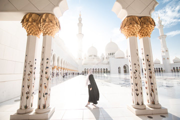 Traditionally dressed arabic woman standing on sun shine wearing black burka visiting Sheikh Zayed...