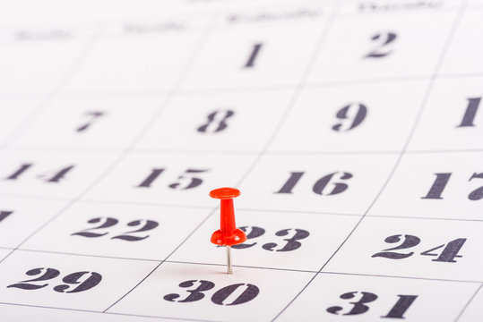 selective focus of red pin marking number 30 in calendar