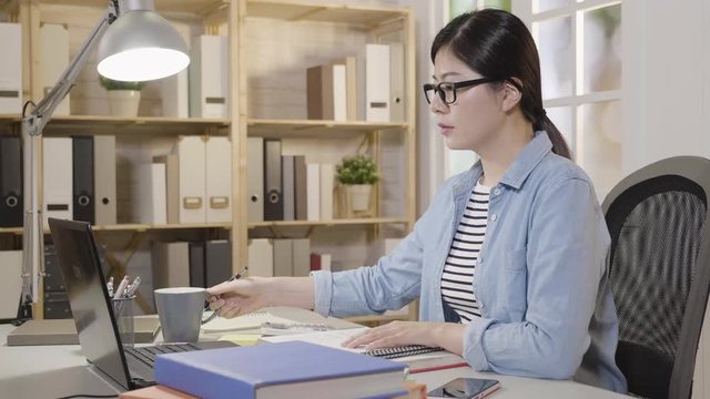 slow motion of young college girl stop writing holding a cup drinking tea let the brain rest a while. smiling female student studying prepare for university final exam by laptop computer at home.