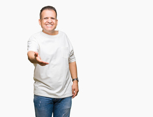 Middle age arab man wearig white t-shirt over isolated background smiling friendly offering handshake as greeting and welcoming. Successful business.