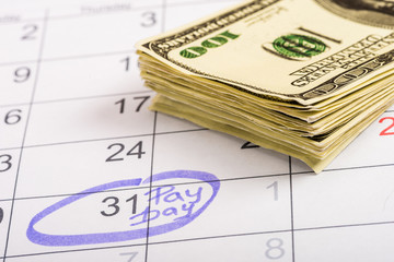 selective focus of dollar banknotes, calendar with marked number 31 and 'pay day' lettering