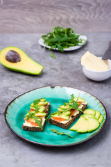 Tasty bruschetta with salmon, butter, avocado and arugula on a plate