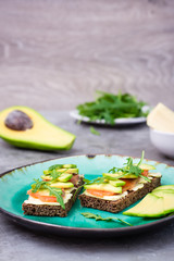 Ready-to-eat bruschettas with salmon, butter, avocado and arugula on a plate