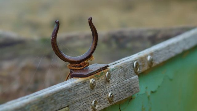 Medium closeup of rusty old oarlock on an old wooden rowboat. Cobwebs. Cape Cod.