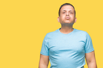 Middle age arab man wearing blue t-shirt over isolated background puffing cheeks with funny face....