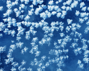 Snowflakes as a snow butterflies over frozen icy river. Frosty nature background.
