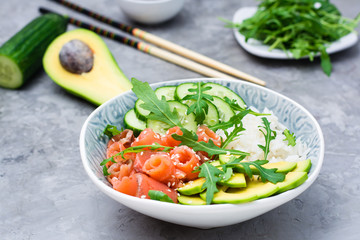Poke bowl with salmon, cucumber, avocado, arugula and seasame seeds. Ready-to-eat appetizer