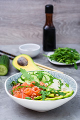 Salmon poke with avocado, arugula and cucumber in a bowl