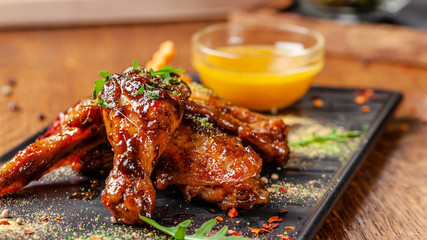 The concept of Indian cuisine. Baked chicken wings and legs in honey mustard sauce. Serving dishes...