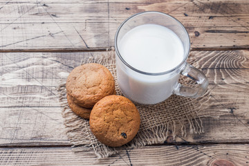 Natural oatmeal cookies and a glass of milk on a wooden background. Rustic style.