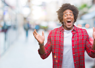 Afro american man over isolated background celebrating crazy and amazed for success with arms raised and open eyes screaming excited. Winner concept