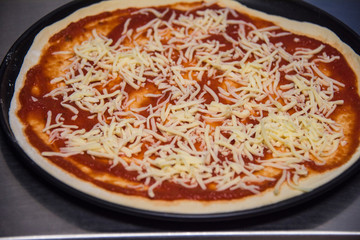 Pizza roh belegt mit Käse und Tomatensauce