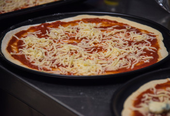 Pizza roh belegt mit Käse und Tomatensauce