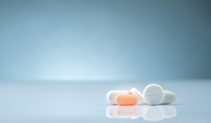 Pharmacy drugstore product. Pile of orange and white tablets pill on gradient background. Different...