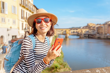 Fototapeta premium Happy traveler asian women on a vacation in Florence admiring view at the Ponte Vecchio famous landmark during trip in Italy, Europe