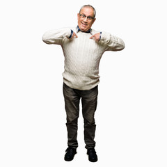 Fototapeta premium Handsome senior man wearing glasses and winter sweater looking confident with smile on face, pointing oneself with fingers proud and happy.