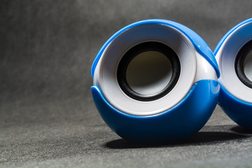 Portable small speakers for music. Plastic. Black background. Blue and white colors. Round shape. Modern equipment. Technologies.