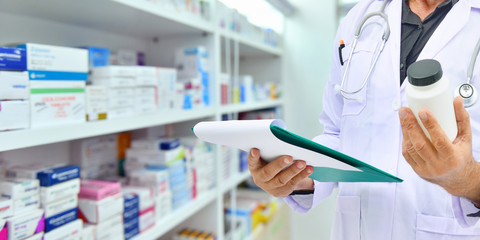 Pharmacien tenant une bouteille de médicament et une tablette informatique pour remplir une ordonnance dans une pharmacie de pharmacie