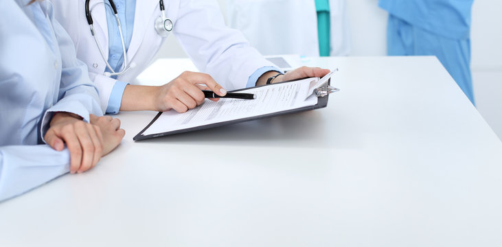 Doctor and patient discussing something, just hands at the table, white background - Powered by Adobe