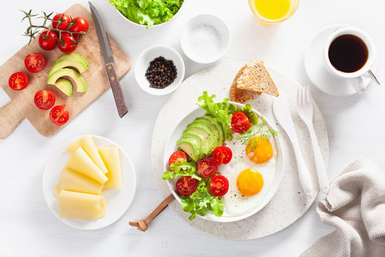 healthy breakfast flat lay. fried eggs, avocado, tomato, toasts and coffee