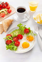 healthy breakfast with fried eggs, avocado, tomato, toasts and coffee