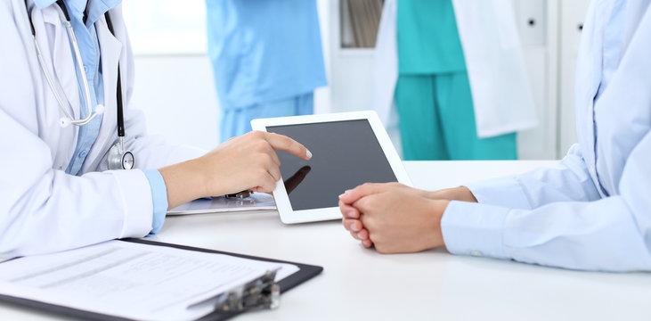 Doctor and patient discussing something, just hands at the table, white background