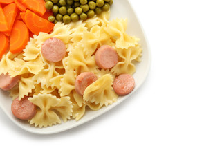 Plate with delicious macaroni, vegetables and cut sausages on white background