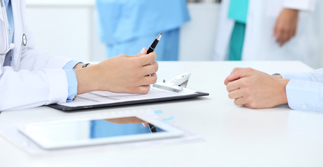 Doctor and patient discussing something, just hands at the table, white background