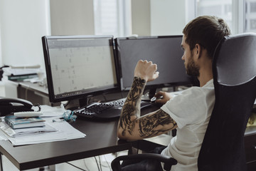 man with tattoos working in the office