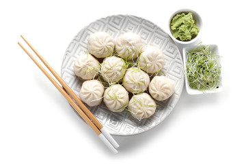 Plate with tasty Chinese dumplings, wasabi and sprouts on white background