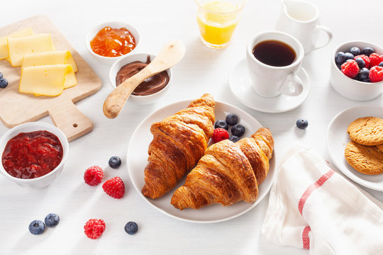 healthy breakfast with granola, berry, nuts, croissant, jam, chocolate spread and coffee