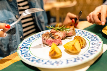 Woman eating delicious rare beef steak in restaurant