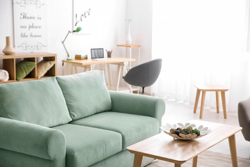 Stylish interior of living room with comfortable sofa and wooden table