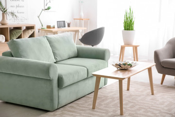 Stylish interior of living room with comfortable sofa and wooden table
