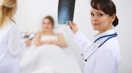 Fototapeta premium Female doctor at the background with patient. Physician at work