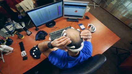 Top view of a man sitting and putting on a bio-signal EEG headset