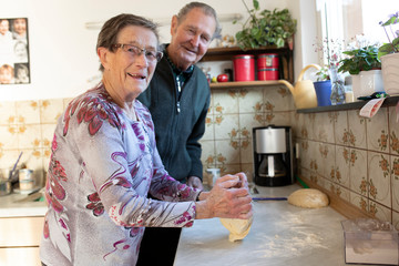 Seniorenpaar backt zuhause ein Brot