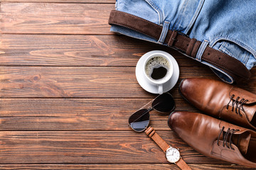 Stylish male clothes with accessories and cup of coffee on wooden table