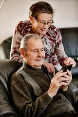Senior, Seniorin, Seniorenpaar surft gemeinsam auf einem Smarphone im Internet