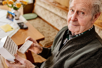 Senior nimmt seine Tabletten ein aus einer Medikamentenbox