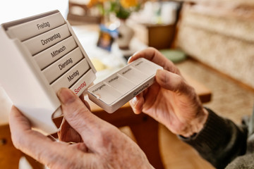 Senior nimmt seine Tabletten ein aus einer Medikamentenbox