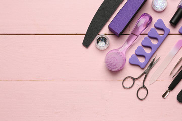 Set of professional tools for pedicure on color wooden background