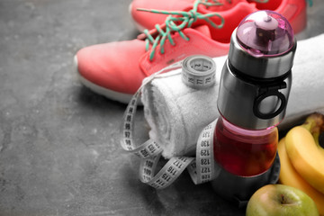 Bottle of water, towel, measuring tape and sports shoes on grey background