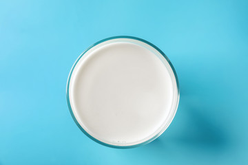 Glass of tasty milk on color background