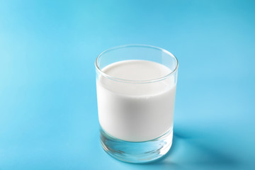 Glass of tasty milk on color background