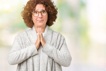 Beautiful middle ager senior woman wearing jacket and glasses over isolated background praying with hands together asking for forgiveness smiling confident.