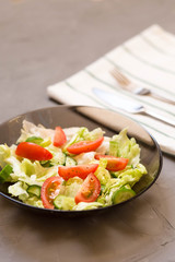 healthy salad, vegetable, tomatoes, cucumbers, iceberg, Cutlery, kitchen towel, grey background. Copy space. Vegetarian