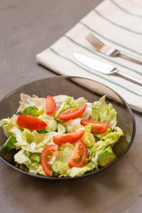 healthy salad, vegetable, tomatoes, cucumbers, iceberg, Cutlery, kitchen towel, grey background. Copy space. Vegetarian