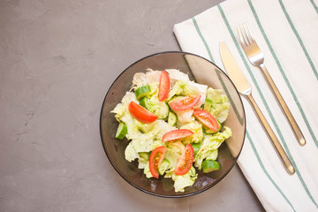 healthy salad, vegetable, tomatoes, cucumbers, iceberg, Cutlery, kitchen towel, grey background. Copy space. Vegetarian
