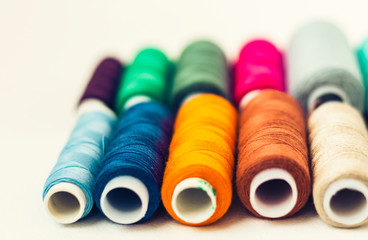 Colored sewing thread coils on white background with copy space for text.
